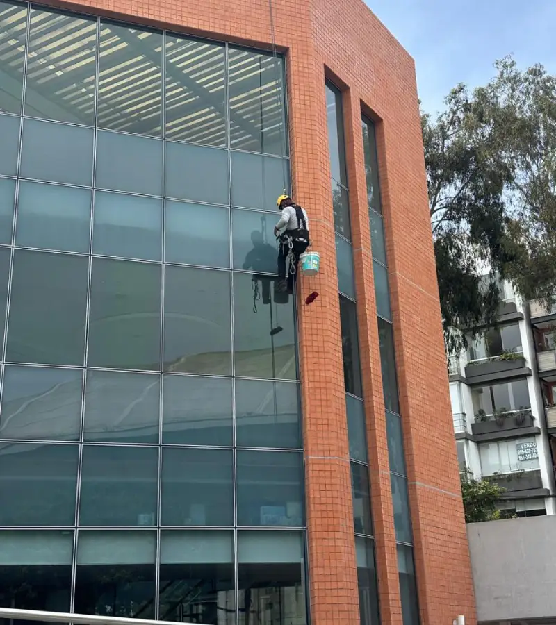 Personal realizando limpieza de fachadas en altura de edificio corporativo con equipo especializado
